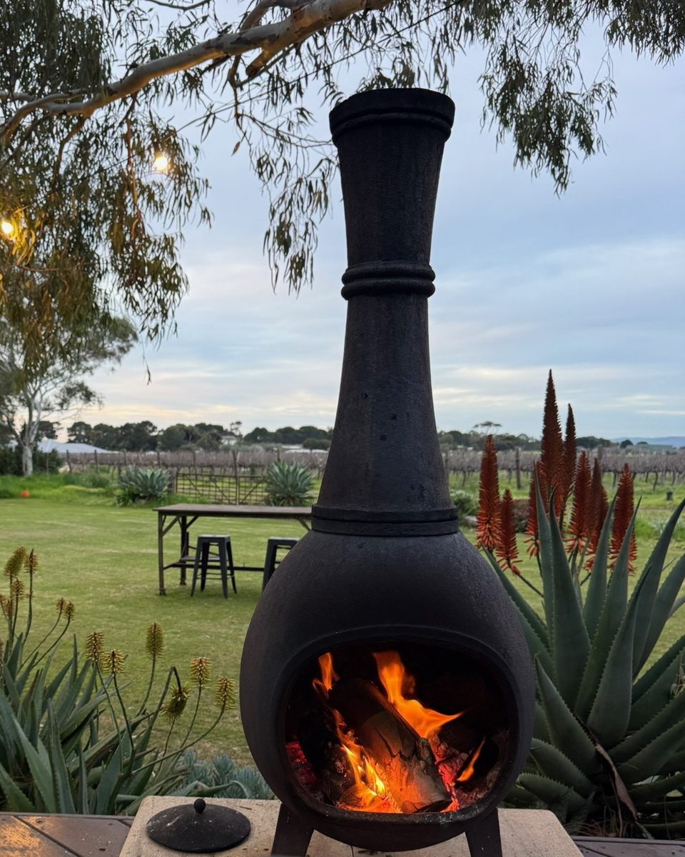The cast-iron chiminea alight on the deck, festoon lights in the gum tree and the vineyard behind