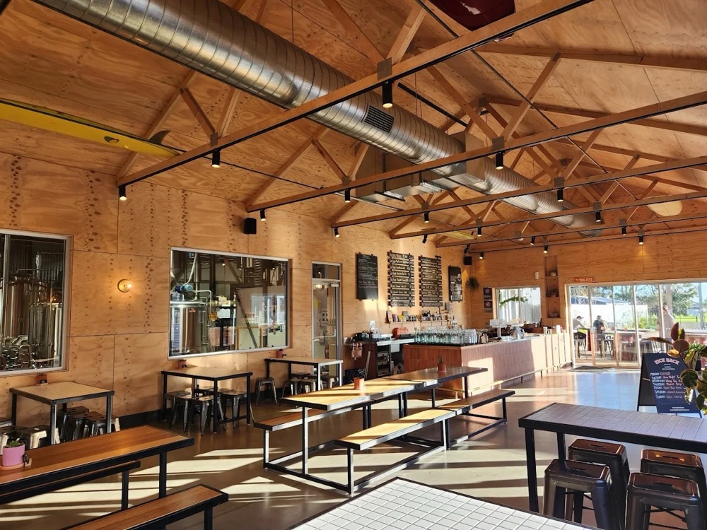 Kick Back Brewing's timber taproom in Aldinga, the brewhouse behind glass and afternoon sun across the tables