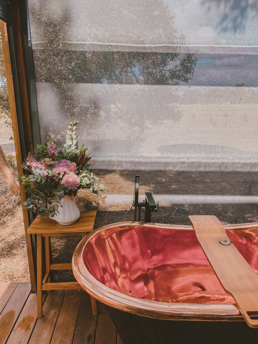 The copper bath with its timber caddy and a vase of flowers
