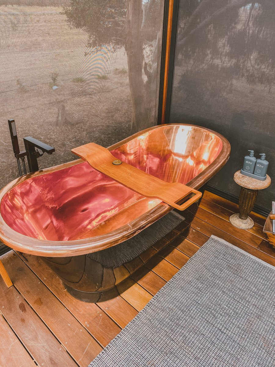 The copper bath in the corner of the bath deck, a bath caddy across it