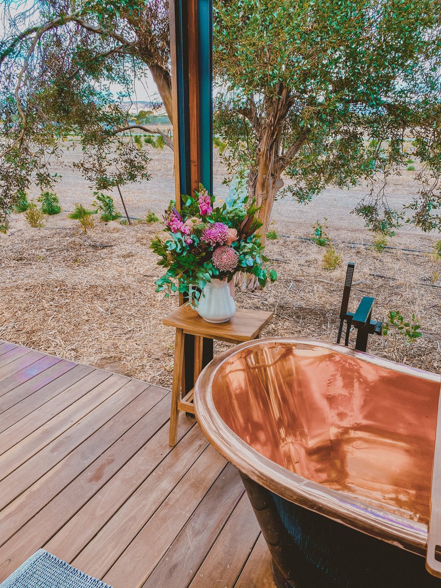 The copper bath beside a stool with flowers, the deck and gums around it