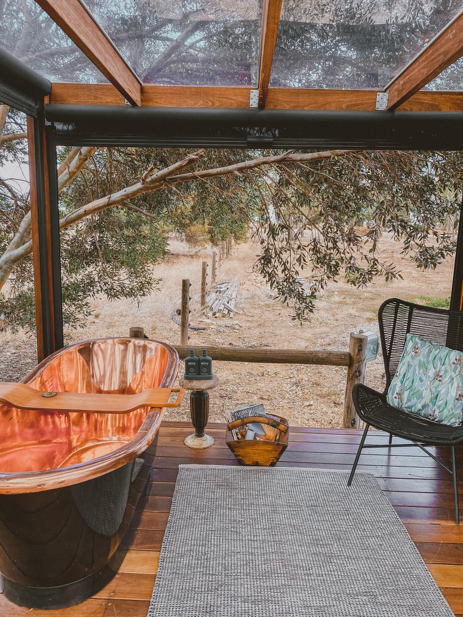 The bath seen through the glass pergola, a chair and cushion beside it