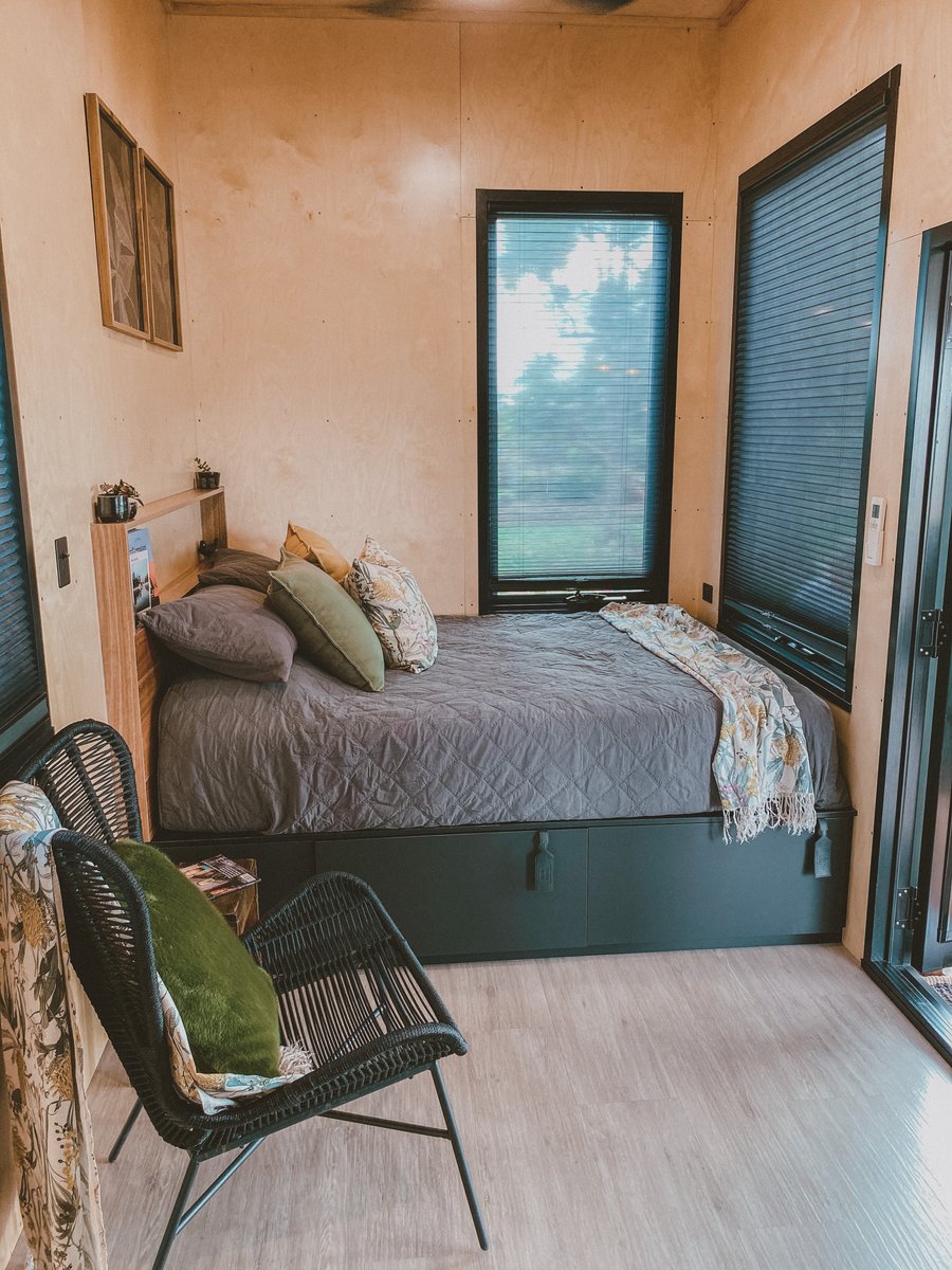 The bedroom: queen bed with soft cushions, a wicker chair and blackout blinds