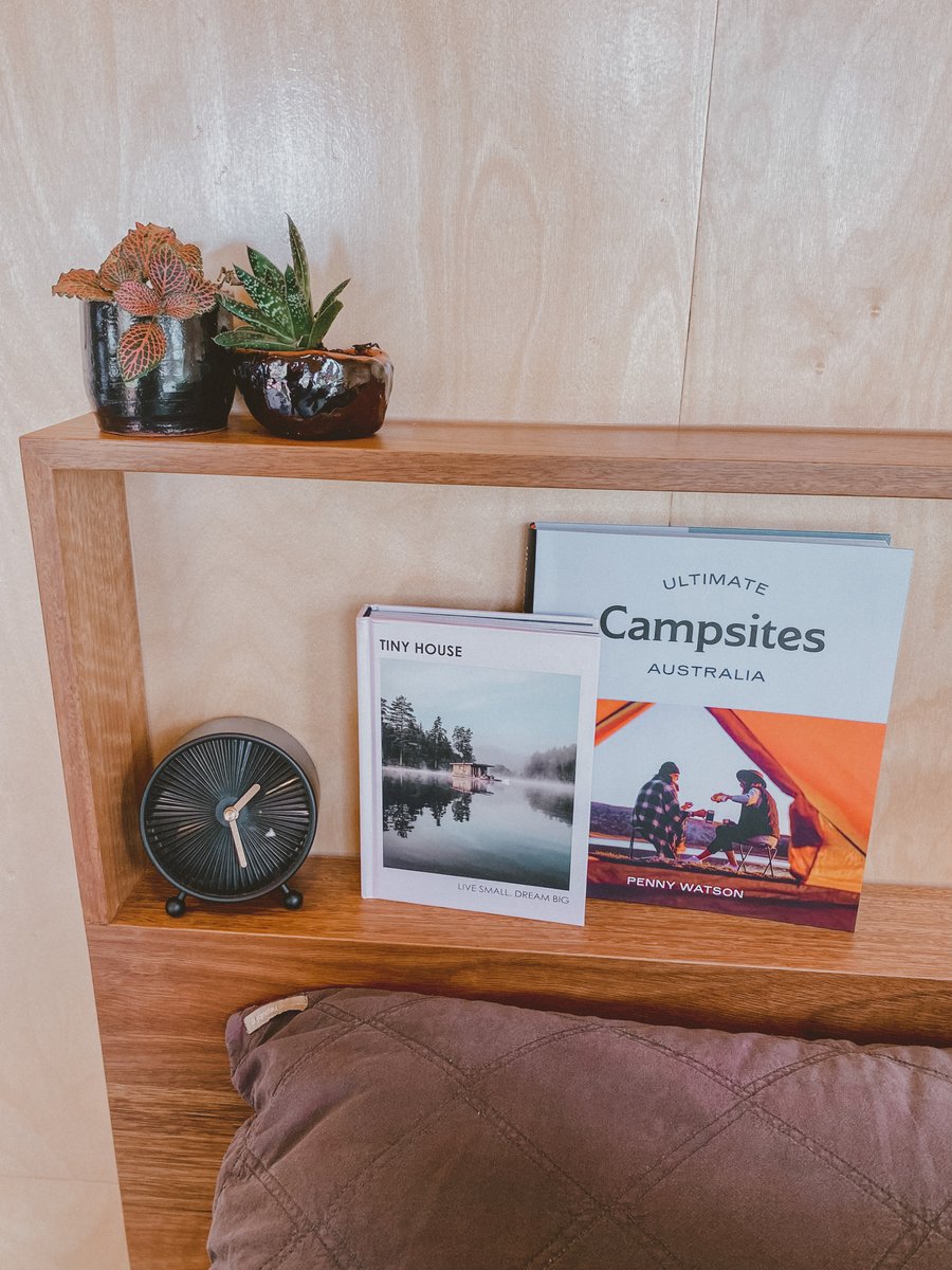 A bedside shelf with books, a clock and plants