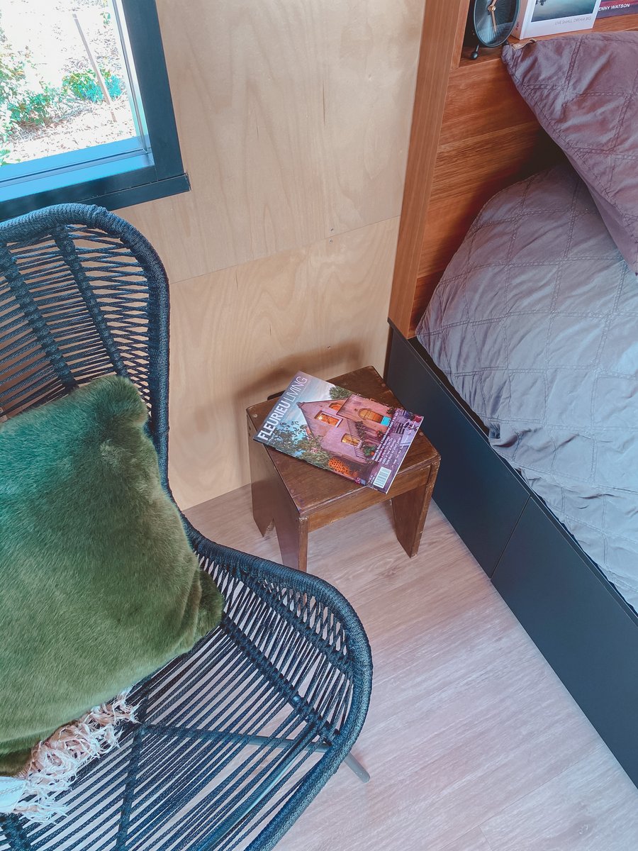 A wicker chair with a velvet cushion beside the bed