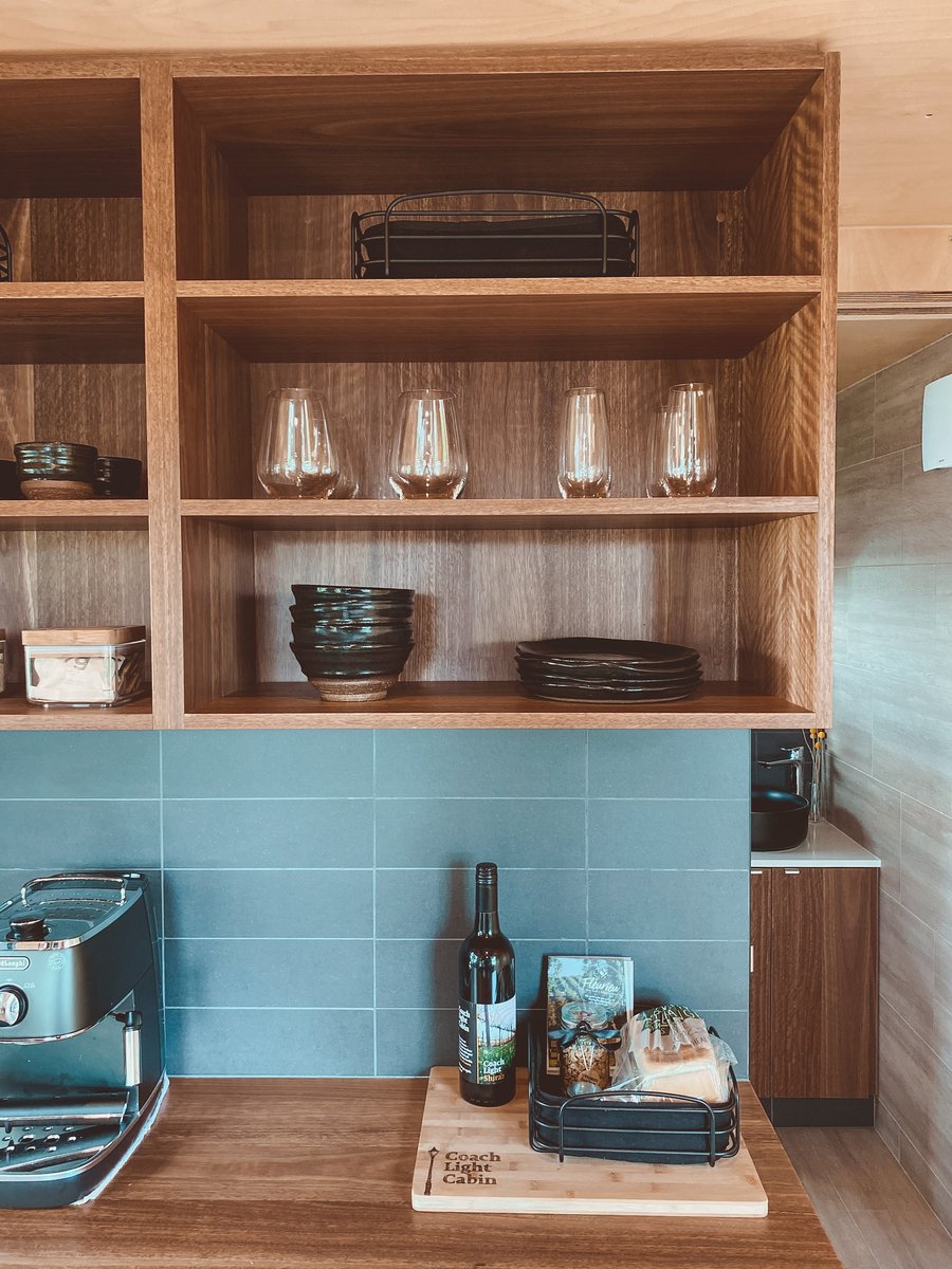 Open timber shelves with glassware above the kitchen bench
