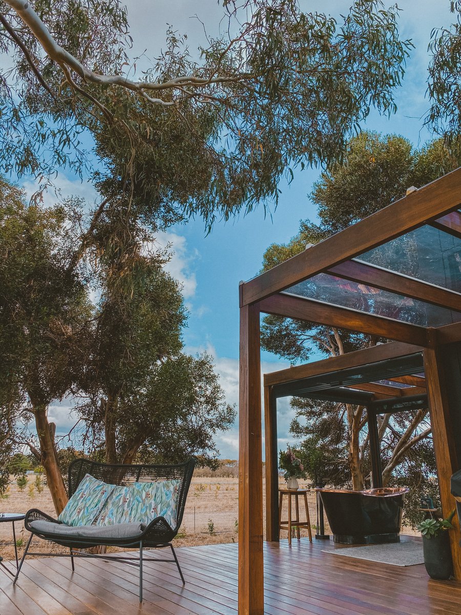 An outdoor chair under the pergola, the deck looking out to the gums