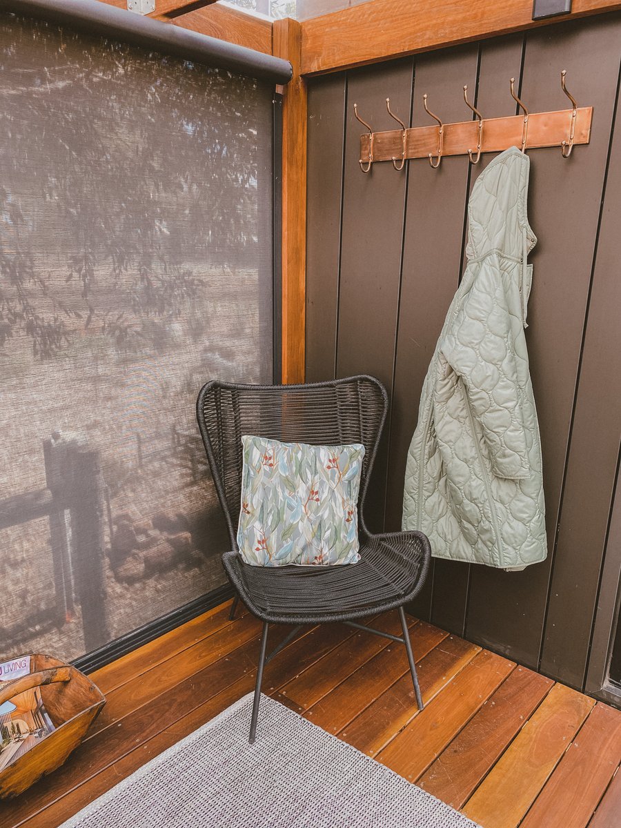 A robe on a timber hook beside a chair with a cushion